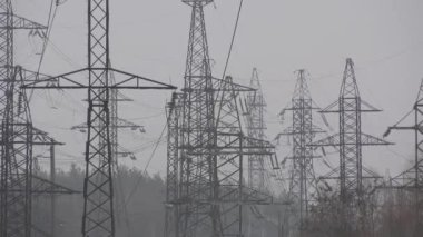 Gökyüzüne karşı elektrik kabloları olan yüksek voltajlı birçok uzun metal kule. Elektrik teslimatı. Elektrik ve ışık tedarikçisi. Enerji güvenliği. Elektrik fiyatları. Enerji sektörüne darbe