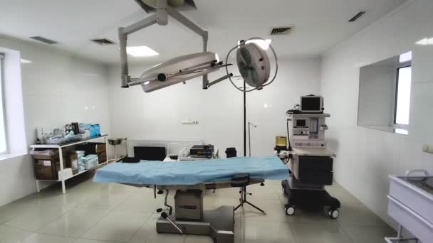 病院内の手術室 中央にはランプ付きのテーブルがあります 側には人工呼吸器 手術器具付きのテーブルがあります 病人への外科的ケアの提供 — ストック動画