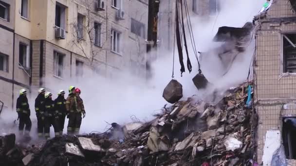 ウクライナのドニプロ 2023年1月14日 全体とヘルメットの救助者は ロシアのミサイルに見舞われたアパートの建物の遺跡に立っています 煙は瓦礫の下から立ち上がる クレーンはコンクリートを持ち上げる — ストック動画