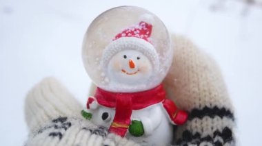 Snowman in winter mittens on a background of white snow in winter. Christmas Holidays and New Years Eve