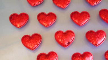 Scarlet shiny hearts on a light background. Backgrounds and textures