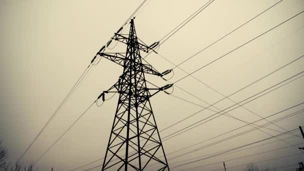 冬の灰色の空を背景に電気線と金属高電圧線 電気の生産と輸送 ウクライナ人の家で光 エネルギーに打撃を与える — ストック動画