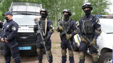 Kharkiv, Ukraine - May 29, 2021: Policemen in bulletproof vests, helmets and with machine guns in their hands are at police cars