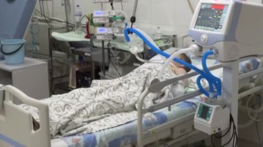 The child lies in bed in the intensive care unit of the hospital. Baby connected to a ventilator