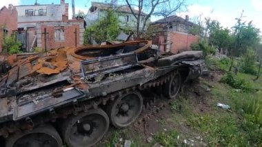 Broken and burned Russian tank against the background of a destroyed house. Real war, Russia attacked Ukraine