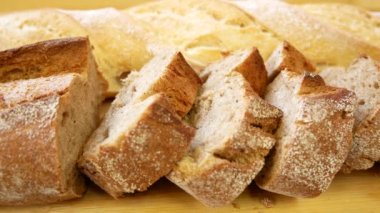 Pieces of chopped rye flour baguette on the table. In the background, a baguette made of white flour