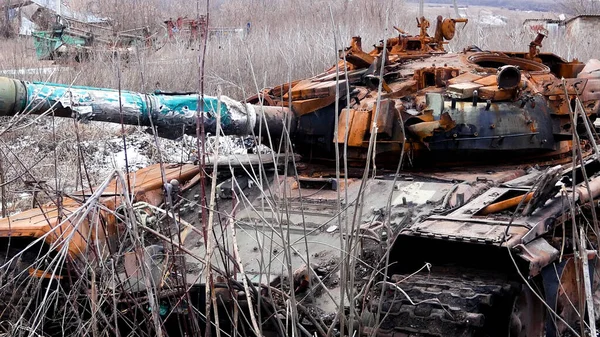 A knocked-out rusted tank stands among the dried grass in a field near the village. Russian-Ukrainian War 2022-2023. The offensive of the Russian army, the occupation of Ukrainian territories