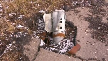 Roket topçu mermisinin metal kuyruğu Ukrayna 'nın bir şehrinin sokağındaki kırık asfalttan sarkıyor. Rus ordusu barış dolu şehirleri bombalıyor. Gerçek Savaş 2022-2023