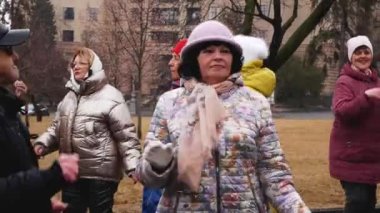 Kharkiv, Ukrayna - Mart, 08, 2023: 55 yaşından büyük yaşlı insanlar, baharda parkta dans ediyor, hayatın tadını çıkarıyor, eğleniyorlar. Yaşlılar için doyurucu bir hayat.