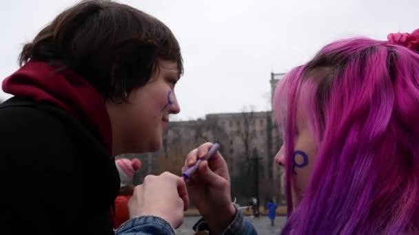 ウクライナのハリコフ 2023年3月8日ピンクの髪をした少女は 誇りを持って参加者に彼女の頬に女性の性別の兆候を描きます 平等の3月 女性は男性と平等な権利のために戦う — ストック動画