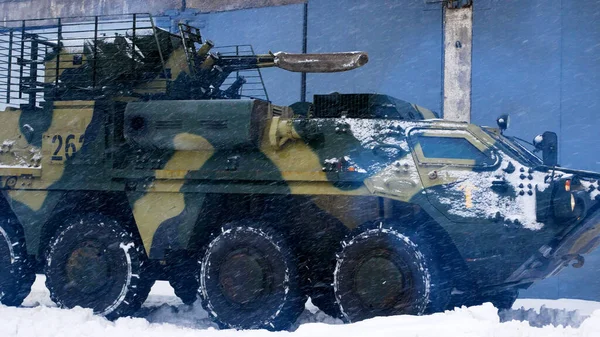 A heavy armored personnel carrier rides along the hangar in the snow. Heavy military equipment goes to combat positions. The Russian-Ukrainian war. Arms supplies and preparations for the Ukrainian