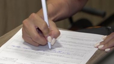Kız kağıtları imzalıyor. Belgedeki sütunları bir kalemle doldurur. Belgeler.