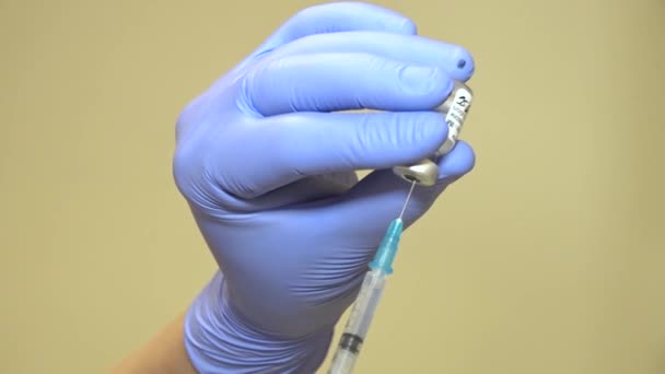 青い医療用手袋の認識できない手は バイアルから注射器にワクチンを描きます コロナウイルスに対する大量接種 — ストック動画