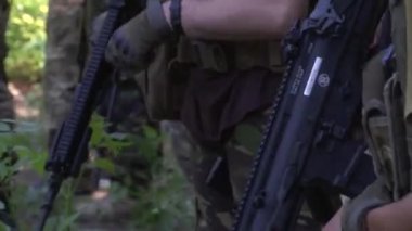 Ormandaki tatbikat sırasında üniformalı ve eldivenli askerler silah topluyor. Gerçek savaş Ukrayna ve Rusya