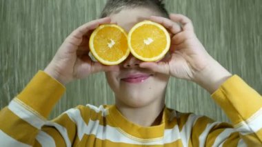 7 yaşında tatlı, mutlu bir çocuk limon dilimleriyle oynar, gözlerini kapatır. Sağlıklı beslenme kavramı. Çocuğun diyetinde bir sürü vitamin var.