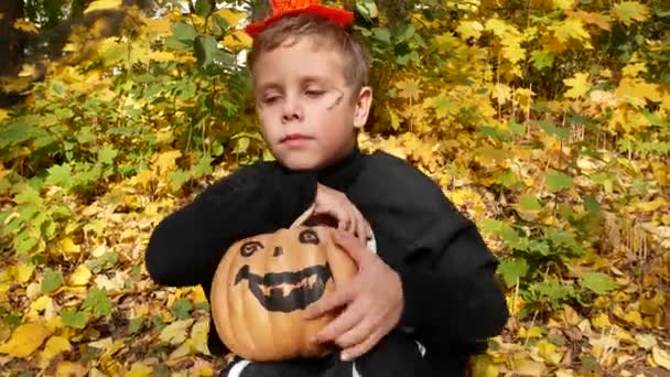 Милий Хлопчик Чорному Костюмі Розфарбованим Гарбузом Руках Сидить Тлі Опалого — стокове відео