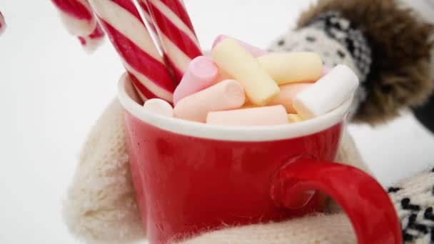 Κόκκινο Κύπελλο Marshmallows Και Ριγέ Γλυκά Στα Χέρια Φόντο Λευκό — Αρχείο Βίντεο
