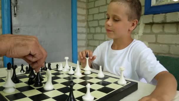 一个6 7岁的男孩下棋时在桌边的达卡玩耍 然后笑着整理数字 — 图库视频影像