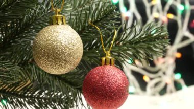 Noel ve Yeni Yıl ağacı süslenmiş altın ve kırmızı Noel toplarıyla süslenmiş arka planda çelenk ışıkları
