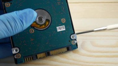 Mavi eldivenli bir ustanın tanınmayan elleri elektronik sürücüyü döndürmek için tornavida kullanır. Bilgisayar ve elektronik onarımları