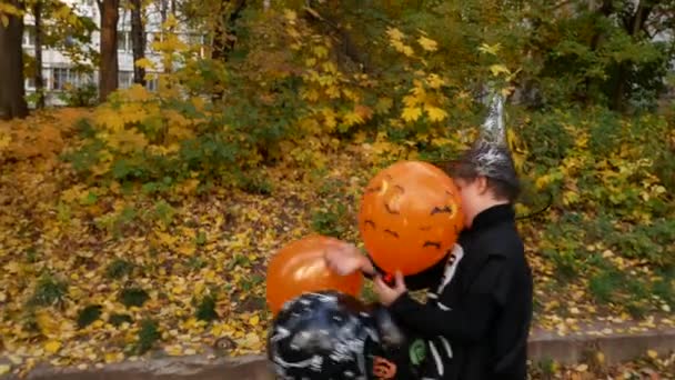 Chłopiec Kostiumie Halloweenowym Bawi Się Pomarańczowymi Czarnymi Balonami Chodniku Jesiennym — Wideo stockowe
