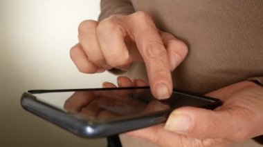 Kız parmağını akıllı telefon ekranında gezdiriyor. Yakın plan. SMS iletileri, sosyal ağlarda iletişim, internet bankacılığı, internet alışverişi, mobil uygulamalarla çalışma.