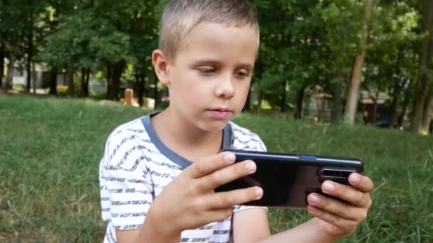 Chłopiec Lat Patrzy Ekran Smartfona Gra Telefonie Komórkowym Parku — Wideo stockowe