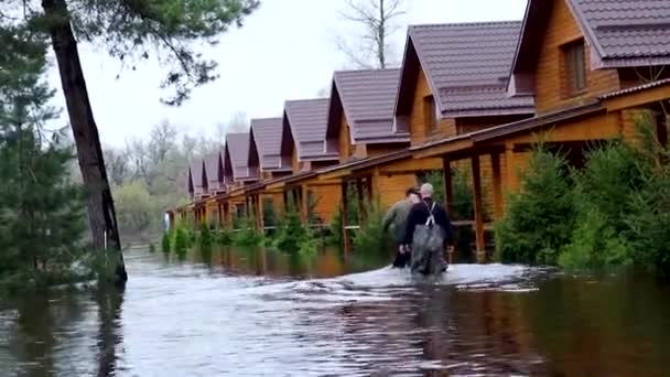 ウクライナのハリコフ 2023年4月17日 ゴム製の保護ハイブーツの救助者は 浸水した家に沿って浸水した通りを歩く 自然災害 強い洪水 浸水した村 — ストック動画