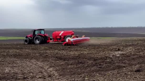 一台装有播种机的拖拉机在春天穿过田野播种麦粒 背景上是犁地 播种运动 粮食作物的种植 粮食保障的概念 — 图库视频影像