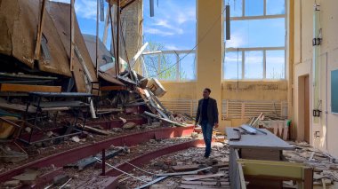 Kharkiv, Ukrayna - Mayıs 04, 2023: Bir üniversite öğretim görevlisi ve profesör, Rus füze saldırısıyla yok edilen bir konferans salonundan geçiyor. 2022 Rusya-Ukrayna savaşı sırasında yıkım ve kayıplar