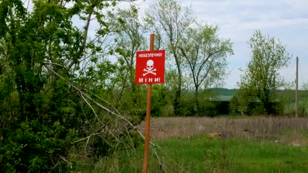 碑文の危険性を持つ赤い看板は 鉱山は占領されていない地域の道路近くのフィールドの危険性を警告しています ロシア ウクライナ戦争2022 2023 — ストック動画