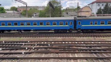 Bir yolcu treni büyük bir şehirdeki büyük bir tren istasyonuna yaklaşarak raylar boyunca yavaşça ilerler. Ön planda bir sürü iç içe geçmiş raylar görebilirsiniz. Demiryolu taşımacılığı ve yolcu