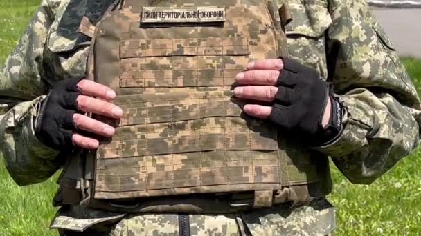 一名身着迷彩服 身穿防弹背心 上面印有领土防卫部队字样的乌克兰士兵站在那里 双手放在防弹背心上 耸了耸肩 — 图库视频影像