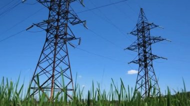 Mavi gökyüzüne karşı yüksek voltajlı elektrik hatları. Metal kuleler ve kablolar. Elektrik taşımacılığı. Tüketiciye elektrik üretimi ve teslimi