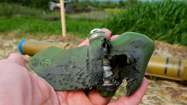 Разорванная противопехотная мина, поврежденная взрывом, с лепестком в руке. Разминирование территории. Русско-украинская война 2022-2023
