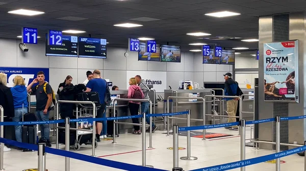 stock image Rzeszow, Poland - June, 15, 2023: People at the check-in counters for flights in the airport building. People check in their luggage at the airport before boarding the plane. On the monitors at the