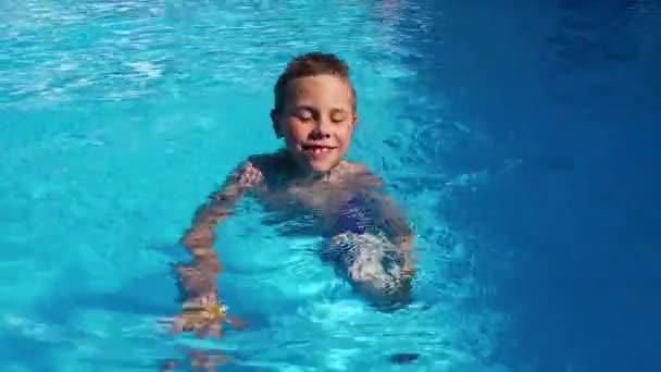一个8 9岁的男孩游泳 在一个有蓝色水的游泳池里游泳 儿童健康改善 — 图库视频影像