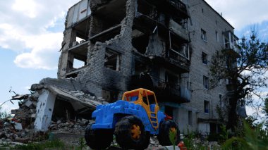 Bir çocuk oyuncağı, Ukrayna 'nın bir şehrinde hava saldırısıyla yıkılan çok katlı bir binanın arka planında. Rus-Ukrayna Savaşı 2022-2023.