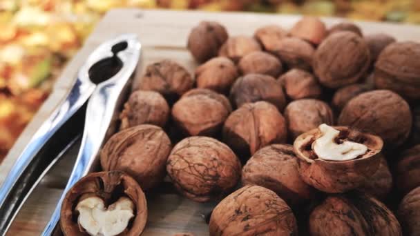 Mnoho Vlašských Ořechů Skořápce Leží Dřevěném Stole Pozadí Podzimního Listí — Stock video