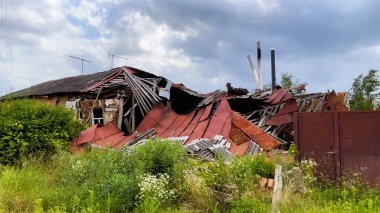 Ukrayna 'nın bir köyünde top mermisi ile yıkılan bir ev. Yıkık çatılı bir ev, molozların altından bacalar görünüyor. Rus-Ukrayna savaşı, gerçek savaş.