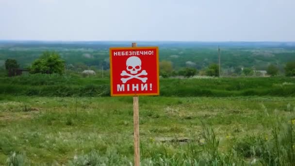 ウクライナの村の背景に対する頭蓋骨のイメージを持つ碑文の注意書き付きの警告サイン ウクライナの村が占領された後の鉱山地帯 — ストック動画