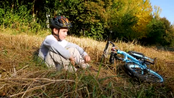 Bisiklet Kasklı Bir Çocuk Yalancı Bir Bisikletin Yanındaki Sarı Çimlerin — Stok video