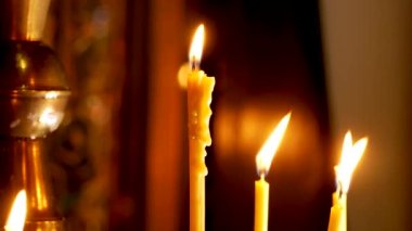 Kilisede yanan mumlar bir haçın arka planında. Kilise hizmeti. Kilise ayinleri, dualar. Mum damlatıyor yanan bir mumu