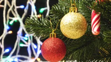 Parlak altın ve kırmızı oyuncaklar, çizgili bir lolipop Noel ağacında. Arka planda Noel ışıkları var. Yeni yıl, Noel süslemesi.