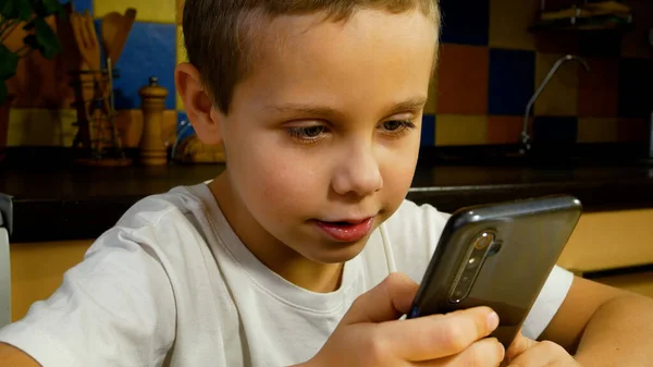 stock image Cute boy looking at smartphone screen and talking. Communication with the help of a smartphone. Games on the gadget.