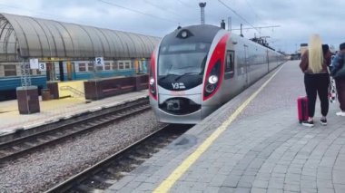 Kharkiv, Ukrayna - 18 Kasım 2023: Şehirlerarası tren istasyon peronuna ulaşır. Arabalar platform boyunca yavaşça hareket ediyor. İnsanlar platformda duruyorlar..