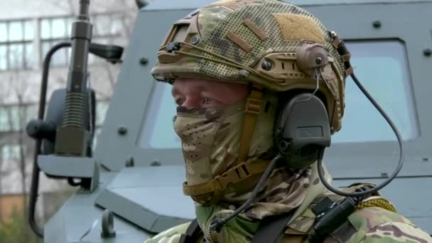 ウクライナ ハリコフ 2023年11月10日 軍用カモフラージュの制服の男性の肖像画 ヘルメット 装甲要員のキャリアの背景に対してバンダナで覆われた顔 ロシア語 — ストック動画