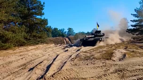 一辆悬挂乌克兰国旗的坦克正在森林的沙滩上行驶 开车通过摄像头 坦克演习 — 图库视频影像