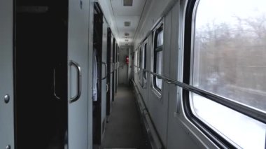 İçinde hareket eden bir trenin vagonu. Kış manzaralarını görebileceğiniz bir koridor ve pencereler..