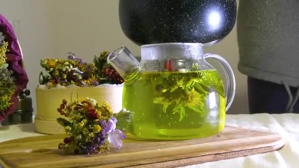 水倒入一个有草药的透明茶壶中 附近有一束药草 森林草本植物芳香茶 — 图库视频影像